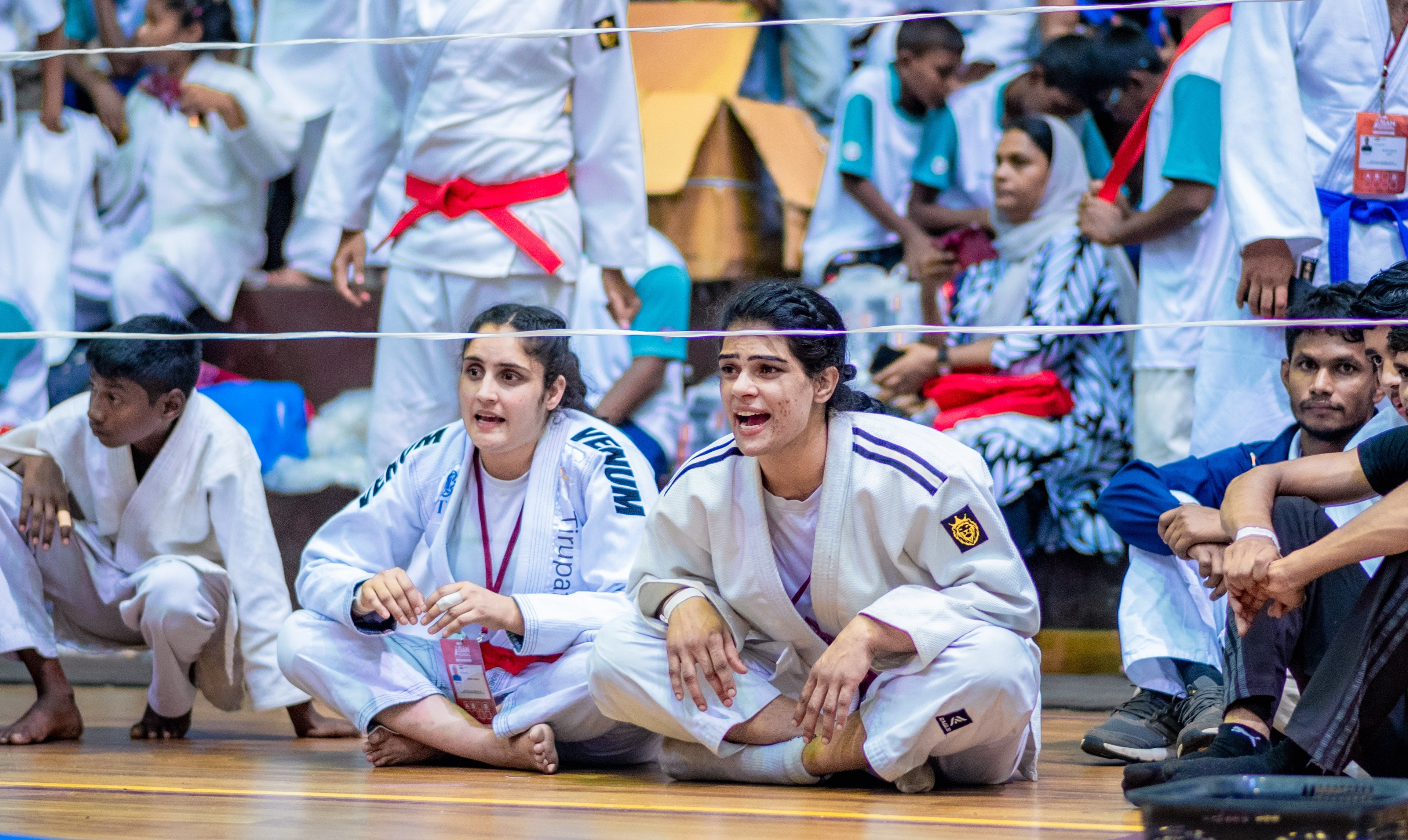 Athletes waiting matside, eyes on the bout in front of them