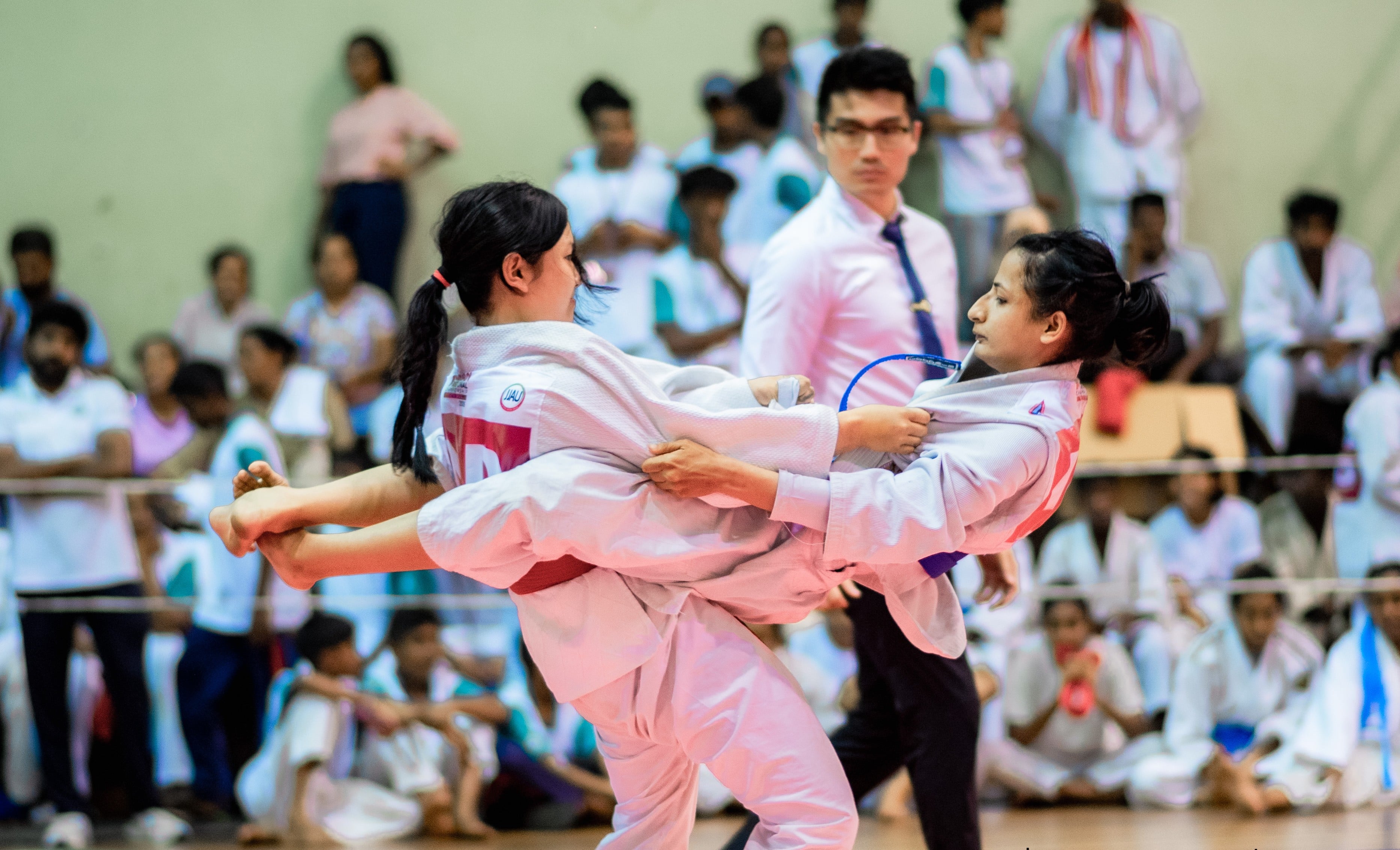Two athletes locked in a grip fight as the referee watches on