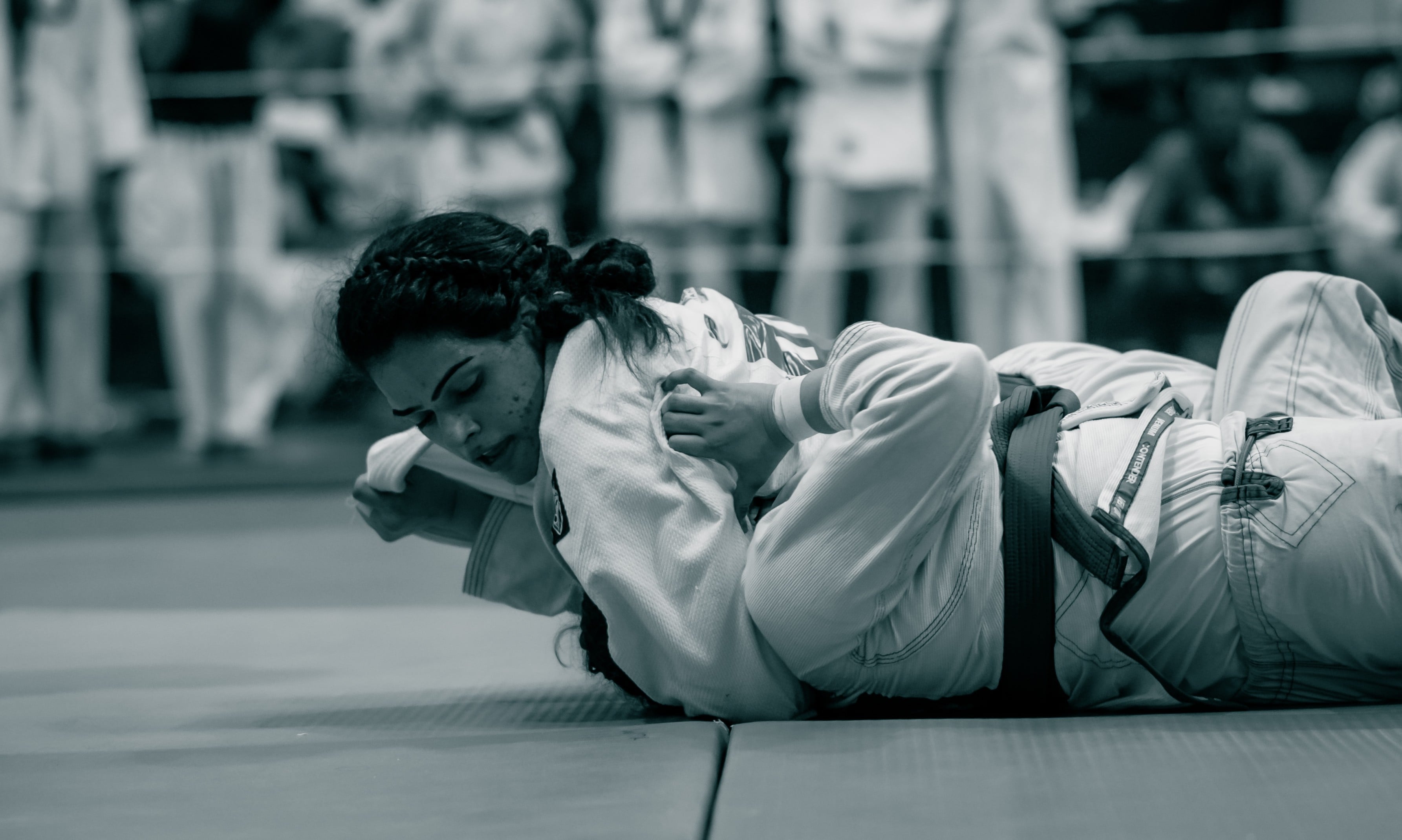 Black and white: an athlete pinned flat to the mat, fighting to turn out