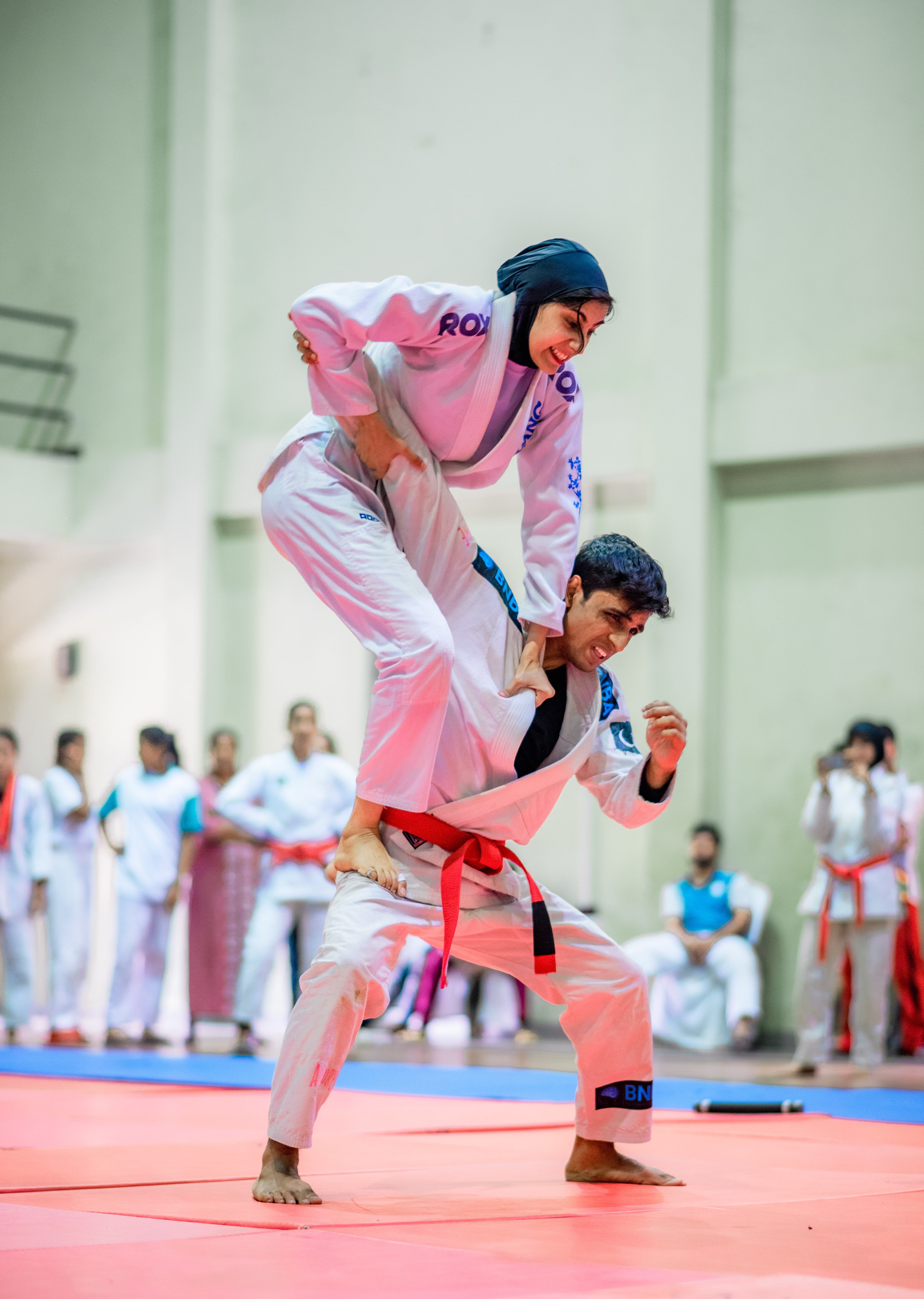An athlete reaches over her opponent's back, working for the throw