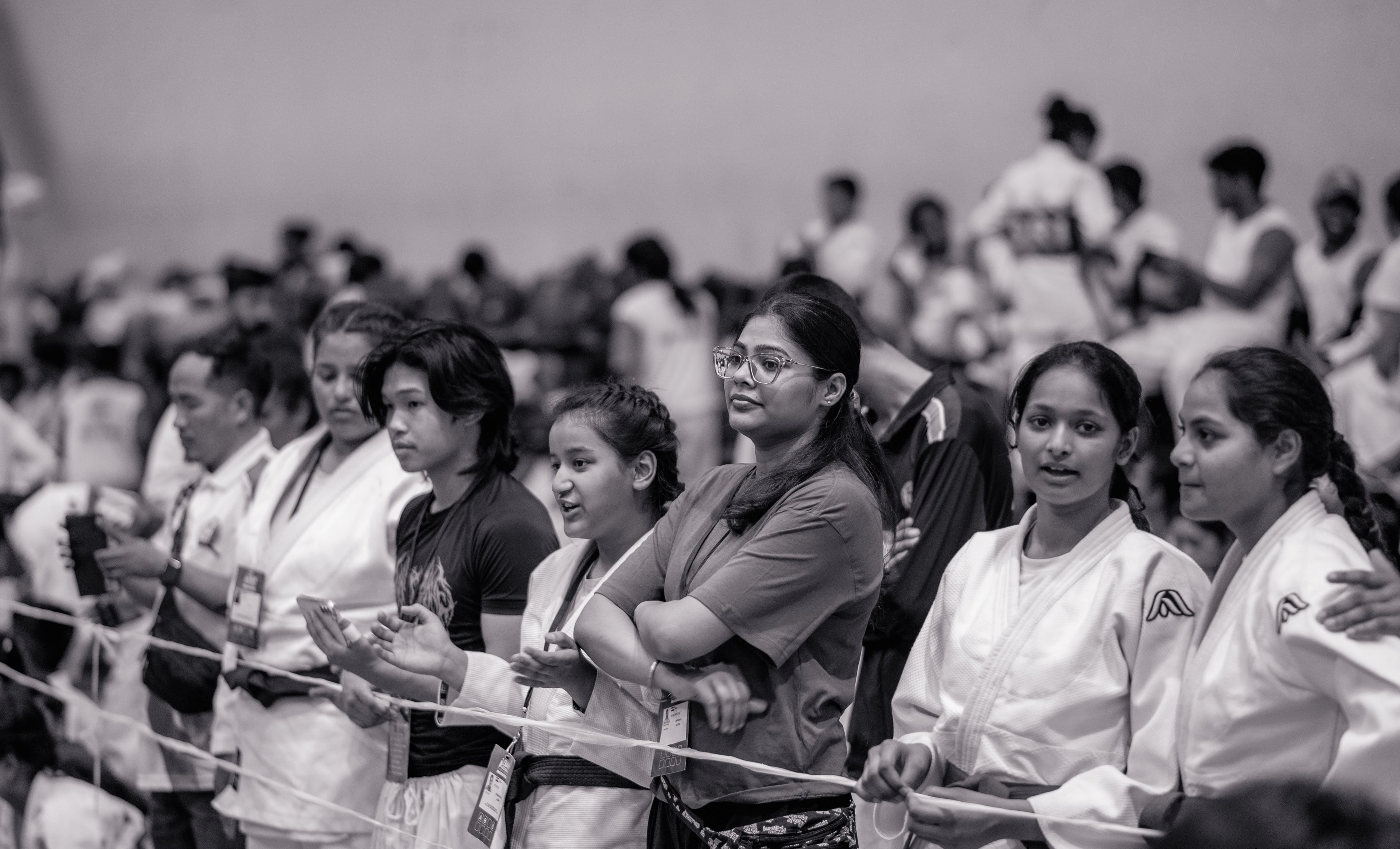 Black and white: a line of spectators pressed against the rope, every face on the action