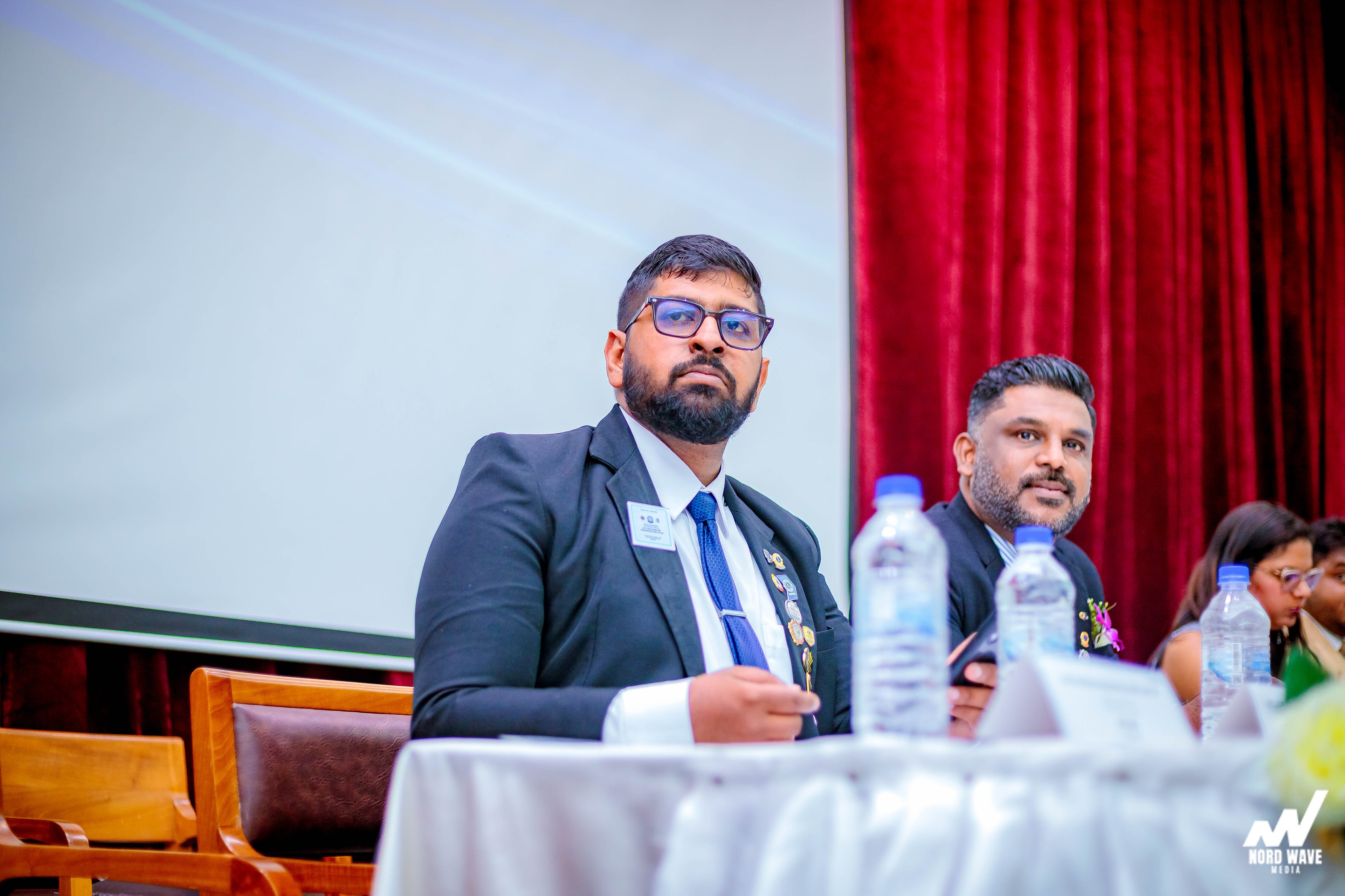 A guest at the head table listens from the stage